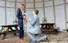 a man kneeling down next to a woman in front of a table with flowers on it