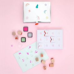 a pink background with wooden blocks, rubber stamps and other crafting supplies on it