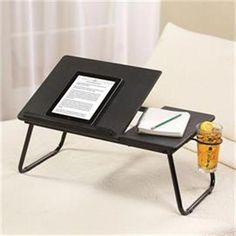 a small table with a tablet on it and a pen resting on the edge next to an open book