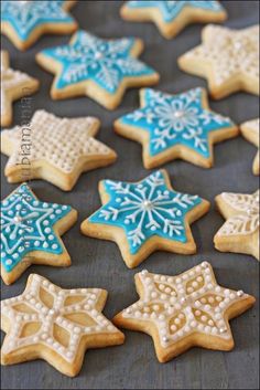 decorated sugar cookies with blue and white icing on a baking sheet in the shape of snowflakes