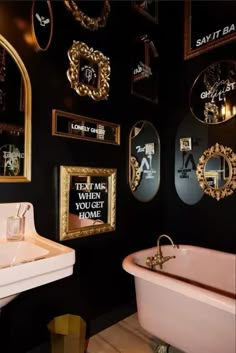 a bathroom decorated in black and gold with pink bathtub, sink and mirror on the wall