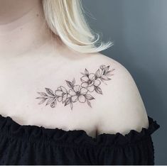 a woman wearing a black dress with flowers on her shoulder and chest tattooing it's upper half