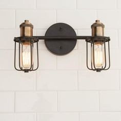 two light fixtures mounted on the wall in an industrial style bathroom with white subway tiles