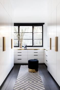 a kitchen with white cabinets and black counter tops next to a large window in the corner