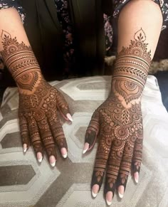 a woman's hands with henna tattoos on her arm and hand, showing the intricate