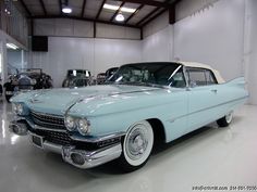 an old blue car parked in a garage