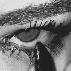 an eye with long black lashes is shown in this black and white photo, while the bottom part of the eye appears to be partially submerged in water