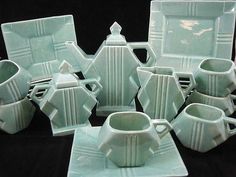 a group of green dishes and cups sitting on top of a black tableclothed surface