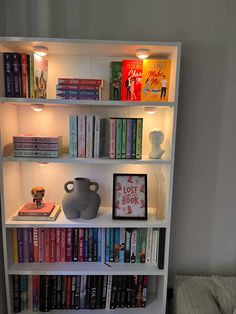 a bookshelf filled with lots of books next to a wall mounted light fixture