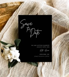 a black save the date card with white flowers