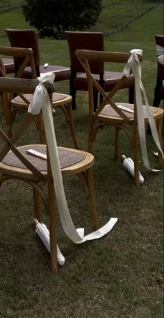 chairs with bows tied to them in the grass