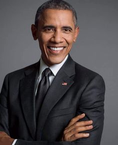 a man in a suit and tie smiling at the camera with his arms folded out