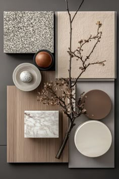 an arrangement of plates, vases and flowers on a gray tablecloth with grey wallpaper