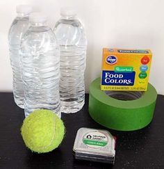 a table topped with water bottles and a tennis ball next to a green tape dispenser