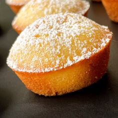 several pastries with powdered sugar on them sitting on a table top, ready to be eaten