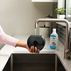 a woman is washing her hands in the kitchen sink