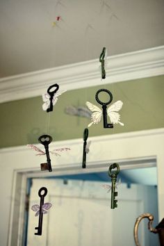 an assortment of keys hanging from the ceiling in front of a door with butterflies on them