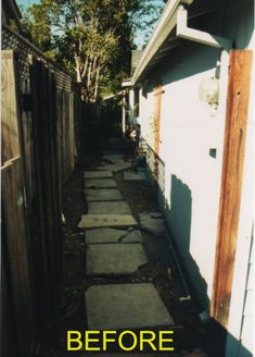 an alley way with stepping stones leading up to the house and trees in the background