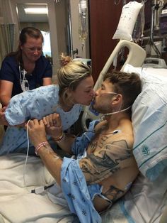 a man laying in a hospital bed kissing a woman's face with an oxygen tube attached to his mouth