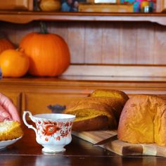 a table topped with loafs of bread next to a cup and saucer