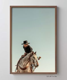 a man riding on the back of a white horse wearing a cowboy hat and black jacket