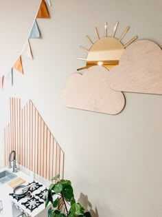 there is a plant on the table in front of the wall with a sun and clouds above it