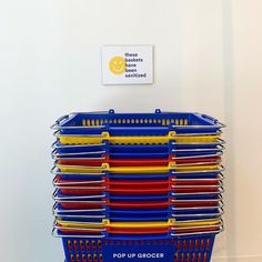 a stack of plastic cups sitting on top of a blue basket next to a sign that says pop up grocery