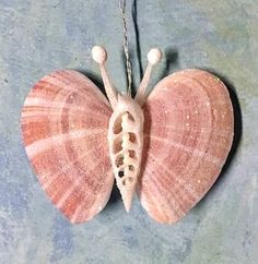 a pink and white butterfly ornament hanging from a chain on a blue surface