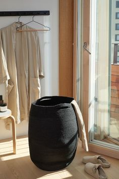 a large black trash can sitting on top of a wooden floor next to a window