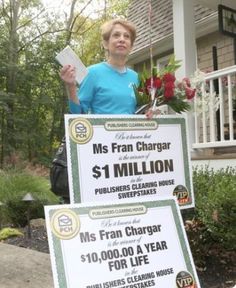 a woman standing next to two large cheque for $ 1 million in front of her house