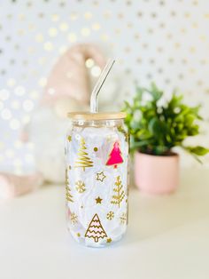 a glass with a straw in it sitting on a table next to a potted plant