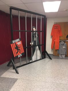 a jail cell with a doll in it and an orange shirt hanging on the wall