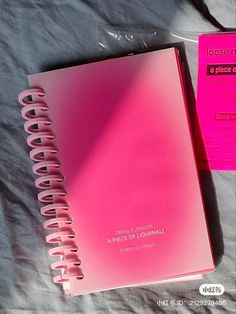 a pink notebook sitting on top of a bed