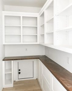 an empty room with white cabinets and wood counter tops on either side of the door