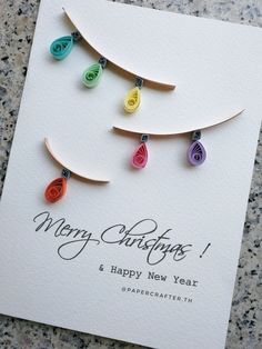 a christmas card with colorful paper ornaments hanging from it