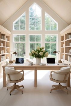 two chairs and a table in front of a large window with open bookshelves