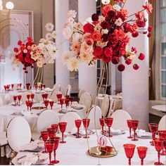 a room filled with lots of tables covered in white table cloths and red glasses