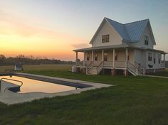 a house with a swimming pool in front of it and the sun setting on the other side