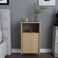 a small wooden cabinet next to a white couch in a living room with grey walls