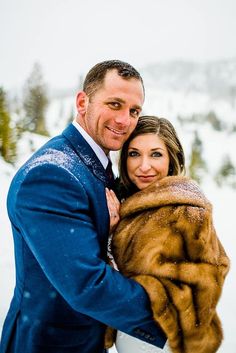 a man and woman hugging each other in the snow