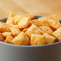 a blue bowl filled with cheetos sitting on top of a wooden table