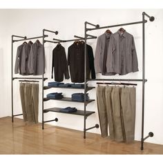 an open closet with clothes and shoes hanging on the wall next to a wooden floor