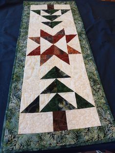 a quilted table runner with trees on it