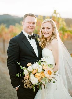 a bride and groom pose for a photo in the vineyard