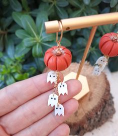 a person is holding two pumpkins with ghost faces hanging from it's chains