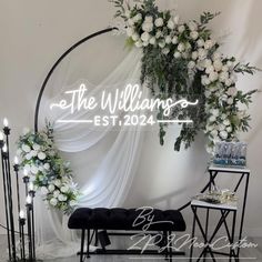 the wedding sign is surrounded by white flowers and greenery, along with black chairs