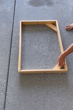 someone is making a frame out of plywood and glue on the floor with their hands