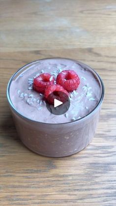 a bowl filled with pudding and raspberries on top of a wooden table