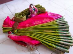 a bunch of green and pink sari on the ground with a doll in it