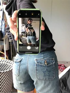 a person is holding up their cell phone to take a selfie with his jeans on